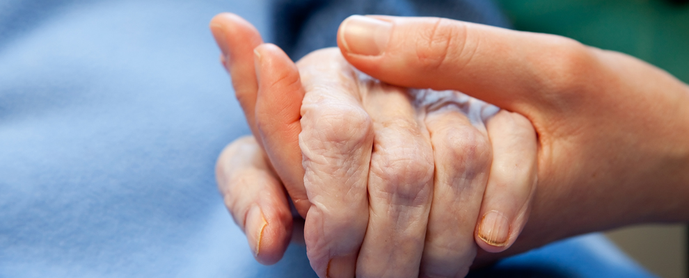 Pflegekraft hält die Hand einer älteren Person